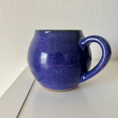 Handmade dark purple spotted mug with round shape.